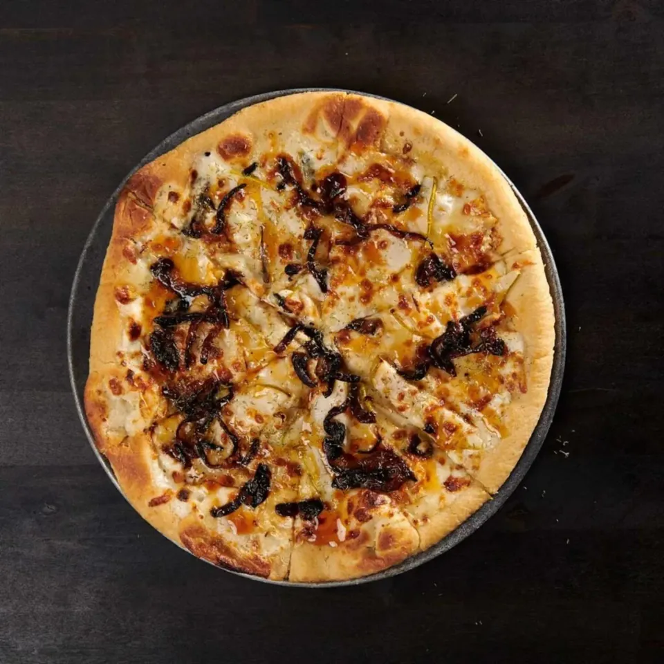 A topped pizza featuring melted cheese, grilled chicken, and caramelized onions on a crispy crust.