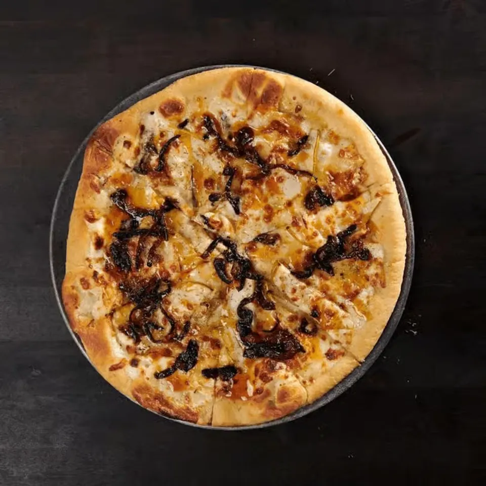 Pizza with melted cheese, grilled chicken, and caramelized onions, served on a round crust.