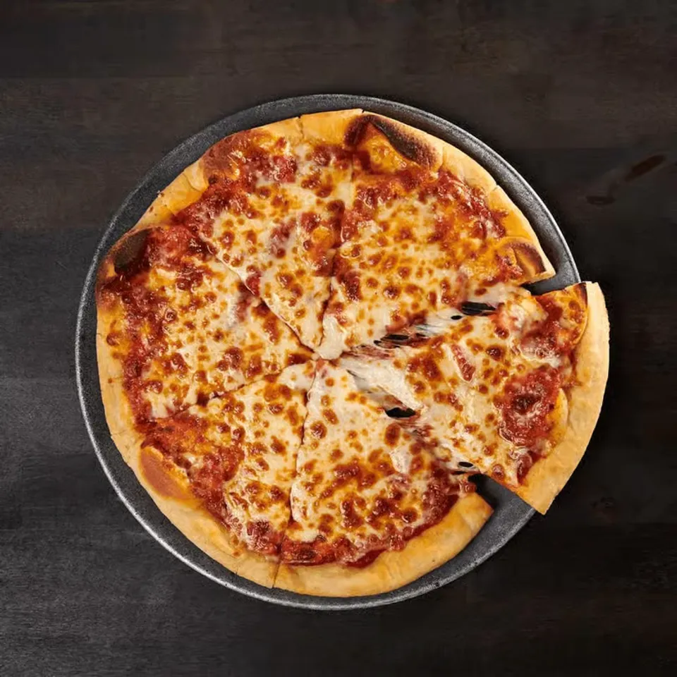 Cheese pizza with a few slices removed, sitting on a black tray against a dark background.