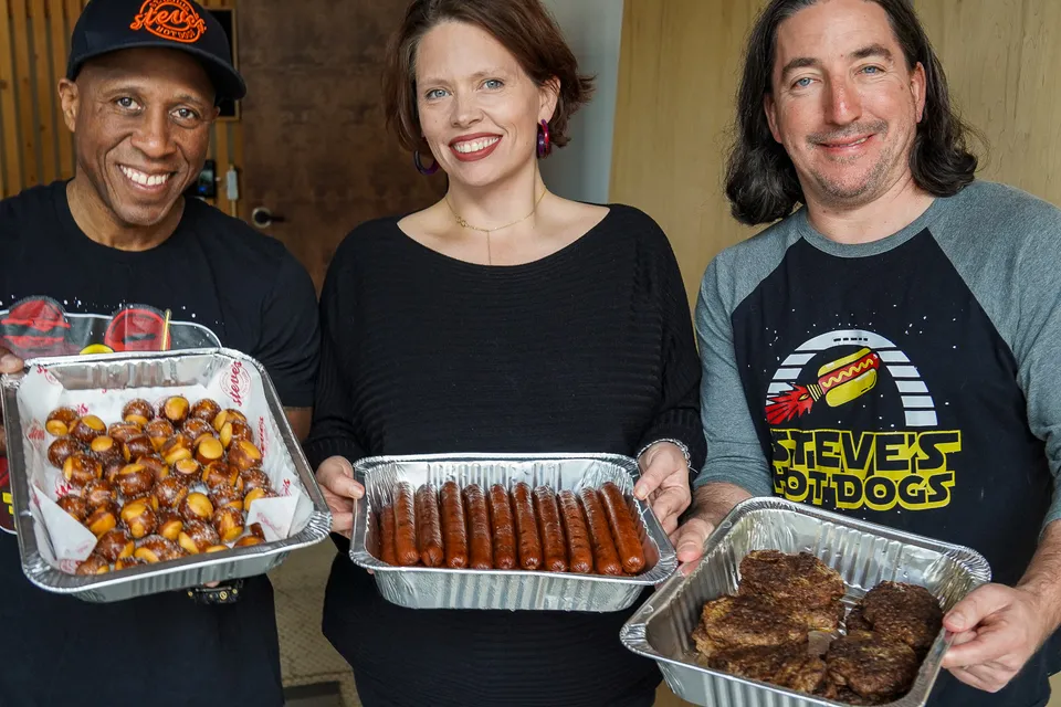 The owners of Steve's Hot Dogs hold pans of food ready to cater an event.