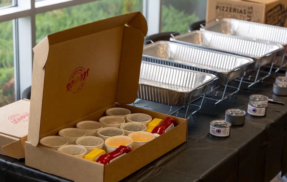 Box of toppings and hot dog bar catering set up at office