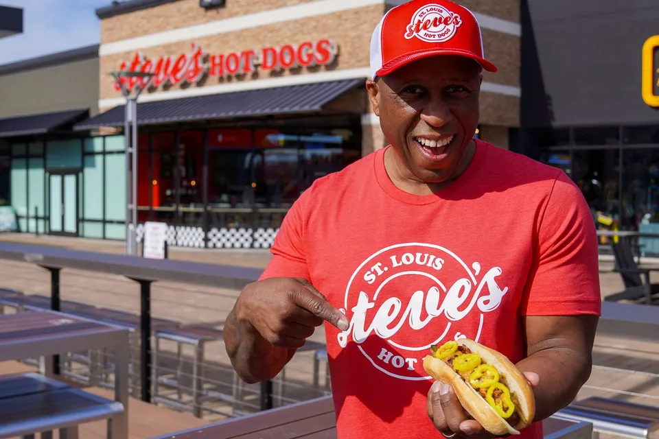Steve Ewing stands outside of Steve's Hot Dogs Chesterfield holding the St. Louis Style Hot Dog.