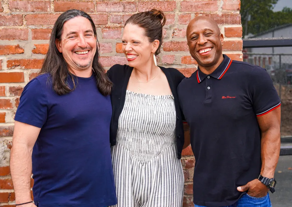 HuSTL Hospitality leaders Marcus Eickenhorst Danni Eickenhorst and Steve Ewing stand in front of a brick wall
